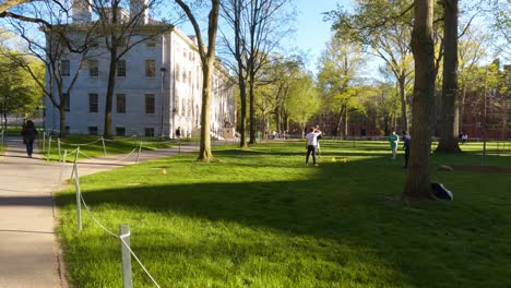 Student-Walking-through-Harvard-Yard,-Looking-at-Other-People-Walking-and-Playing-Games-on-Outside-Campus