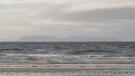 Die-Schottische-Insel-Eigg-Von-Einem-Strand-Auf-Der-Isle-Of-Skye-Aus-Gesehen,-Während-Die-Wellen-Hereinbrechen