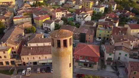 Drone-view-of-a-historical-tower-in-a-small-village-during-a-sunset