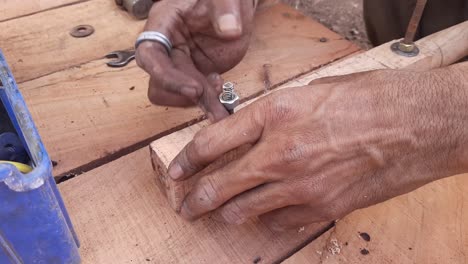 Kart-Painter-is-fixing-the-handle-of-the-wooden-thela-gaadi-by-hand-with-a-nut-bolt