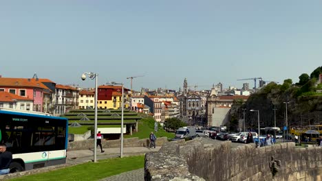 Slow-motion-shot-of-driving-bus-and-walking-people-on-road-of-Oporto-during-sunny-day-with-buildings-in-background