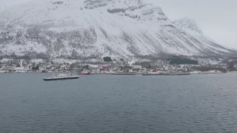 Ciudad-De-Kåfjord-Y-Muelle-Al-Pie-De-Una-Montaña-En-Olddalen,-Noruega-Durante-El-Invierno---Toma-Aérea-De-Drones