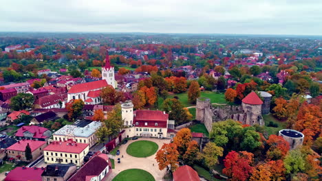 Aerial-backward-moving-shot-over-iconic-medieval-castle-called-Cēsis-Castle-in-Latvia-at-daytime-with-the-view-of-a-town-in-the-background-on-a-cloudy-day