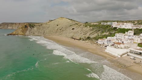 Aerial-shot-of-surfers-waiting-for-waves-along-the-beach-of-a-picturesque-coastal-town