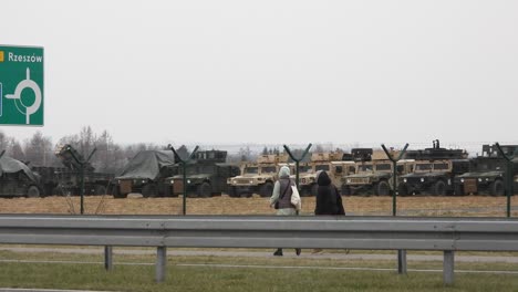Two-women-pass-military-equipment-destined-for-the-Russia-Ukraine-conflict-along-a-busy-urban-road