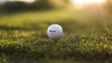 Srixon-Golf-Ball-Placed-on-Tee-Box-at-Golf-Course,-Sunset-with-Sun-Flare