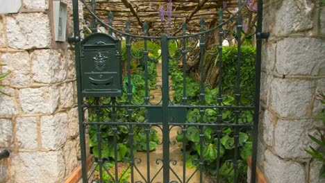 Puerta-De-Hierro-A-Través-De-Los-Jardines-Botánicos-De-Villa-Della-Pérgola-Con-Vides-De-Glicina-En-Crecimiento-En-Capri,-Italia