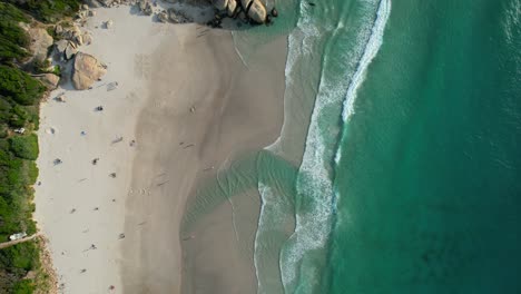 few-tourists-relaxing-on-white-sand-Llandudno-Beach-with-beautiful-ocean-waves-crashing,-aerial