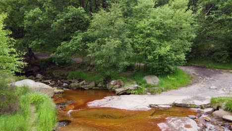 Drone-footage-of-a-meandering-woodland-stream-in-the-Derbyshire-Peak-District-with-water-flowing-over-small-and-large-rocks