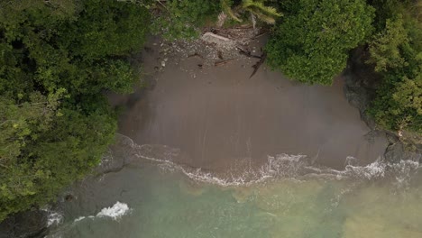 top-down-view-rising-drone-flight-over-a-sandy-beach-of-a-tropical-island-in-the-ocean