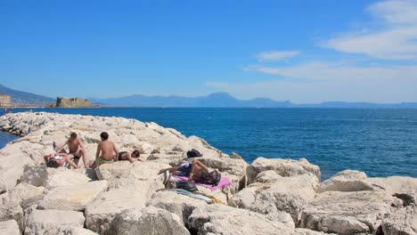Menschen-Sonnen-Sich-Am-Felsigen-Mittelmeerufer-In-Neapel,-Italien