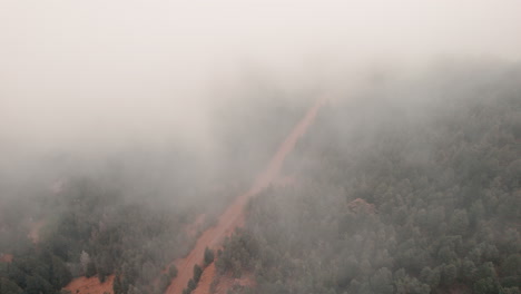 Aerial-bird's-eye-view-over-dirt-road-visible-through-fog,-Cheyenne-Canyon,-Colorado