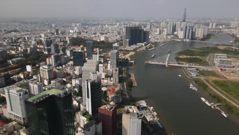 Aerial-View-of-Modern-Ho-Chi-MInh-Cityscape,-riverside-Buildings-and-Towers-on-Sunny-Day,-Establishing-Drone-Shot