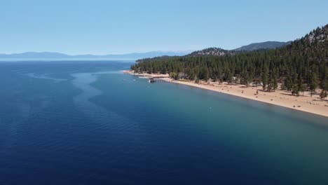 Clockwise-drone-shot-of-Nevada-Beach,-the-forest,-and-the-crystal-clear-water-of-Lake-Tahoe-on-a-clear-day