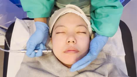 Asiatisches-Mädchen-Bekommt-Eine-Gesichtsbehandlung-Mit-Einem-Saugpeeling,-Um-Abgestorbene-Haut-Zu-Entfernen