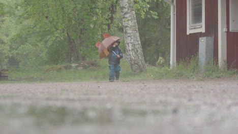 EXTREME-WEATHER---A-child-with-an-umbrella-runs-about-in-heavy-rain