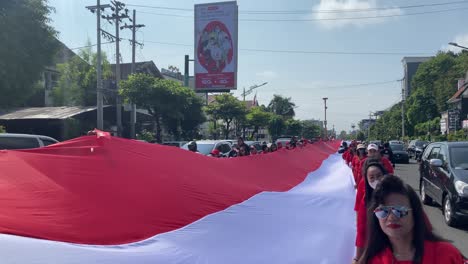 The-stretching-of-the-long-red-and-white-Indonesian-flag-was-carried-by-several-people-through-the-landmark-area-of-the-Tugu-Yogyakarta-monument,-in-the-context-of-Indonesia's-independence