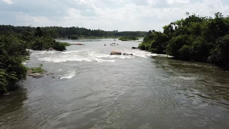Aerial-view-of-drone-zooming-away-from-rafting-boats-going-down-the-Nile-River-in-Jinja,-Uganda,-Africa