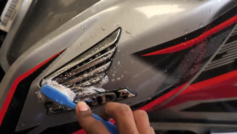 Close-up-shot-of-man-hand-brushing-Honda-logo-of-bike-