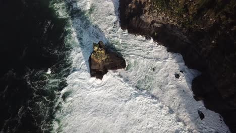 Rock-next-to-the-cliffs-of-Moher-in-the-atlantic-ocean,-big-waves-create-foam,-drone-aerial-top-view