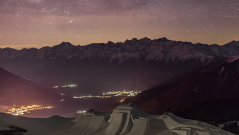 Night-time-lapse-shot-of-orbiting-stars-over-snow-capped-mountain-range---snow-park-for-Suzuki-Nine-Knights-event-in-foreground