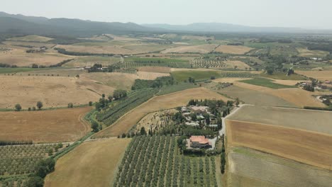Aerial-images-of-Tuscany-in-Italy-cultivated-fields-summer,-Flight-over-an-agricultural-farm-with-neat-crops