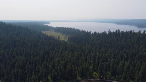 Drone-shot-of-a-golf-course-next-to-Lake-Payette-and-surrounded-by-a-deep-green-pine-forest