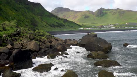 Vik,-Iceland-coast-with-waves-crashing-on-rocks-with-drone-video-moving-forward-through-rocks