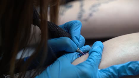 The-tattoo-artist-is-making-a-tattoo-on-a-woman's-leg