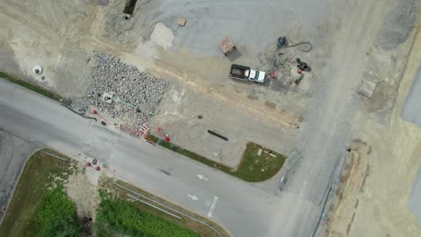 Aerial-view-of-Heavy-construction-equipment-working-at-the-construction-site-near-a-lonely-road-in-a-bright-sunny-day