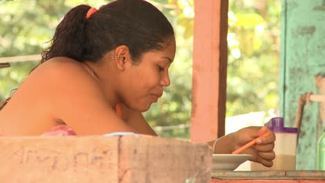 Mujer-Indígena-Comiendo-De-Un-Tazón-En-La-Cocina-Comunitaria-En-Un-Pueblo-Cerca-De-Manaus,-Brail
