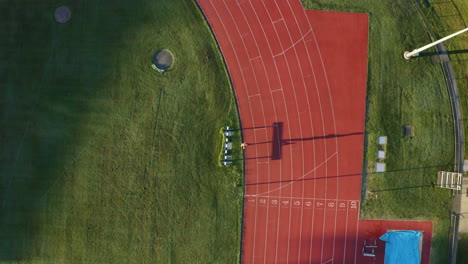 Aerial-4K-Drone-View-Of-Fit-Athlete-Running-Fast-Laps-On-Outdoor-Red-Race-Track