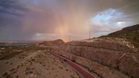 Ascending-over-McKellington-Canyon-in-El-Paso,-Texas-to-see-a-rainshower-casting-a-rainbow