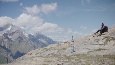 Schwarzer-Bergsteiger-Mit-Rucksack,-Der-Sich-Den-Schweiß-Abwischt-Und-In-Gedanken-Auf-Einem-Berghang-In-Der-Nähe-Des-Matterhorns-In-Der-Schweiz-Ruht