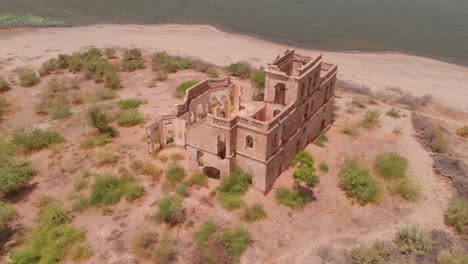 Aerial-Parallax-Shot-Of-Abandoned-Building-On-Small-Island-In-Chotiari-Reservoir-In-Sindh,-Pakistan
