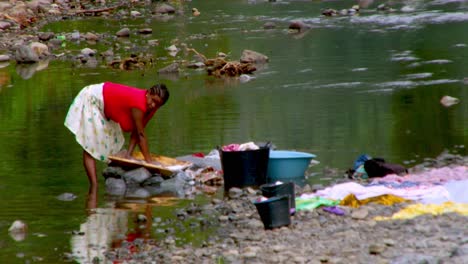 Female-African-Woman-from-São-Tomé-works-hard-to-wash-laundry-by-the-river