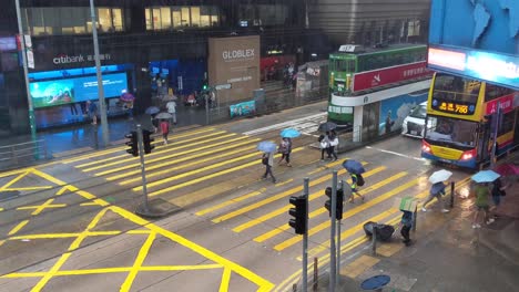 People-holding-umbrella-crossing-road-in-Central,-Hong-Kong-during-rain-storm