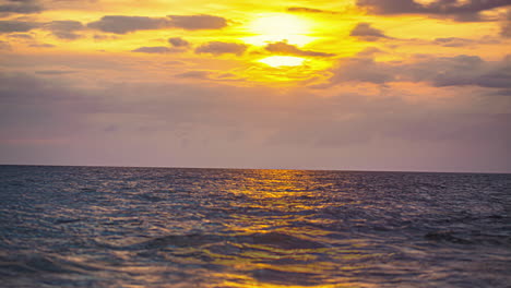 A-golden-cloudscape-sunset-over-choppy-ocean-water-with-the-colors-reflecting-off-the-water---time-lapse