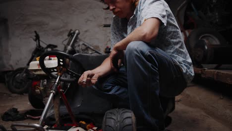 Cinematic-shot-of-mechanic-inspecting-a-chain-lock-standing-in-front-of-his-go-kart