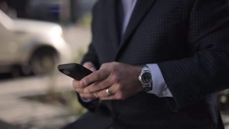 Close-up-of-an-texting-on-mobile-phone-outside-with-blurred-background