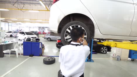 Asian-Man-Technician-Using-Tool-to-Install-Car-Wheel,-Close-Up