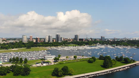 Wide-pull-away-aerial-view-of-sail-boats-in-a-quiet-bay-with-city-skyline-in-the-background