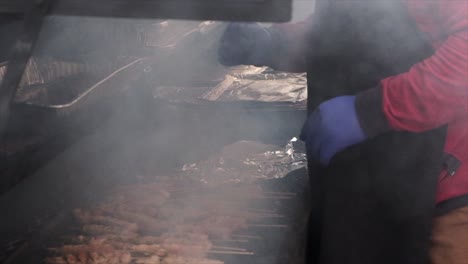 Un-Hombre-Asando-Shish-Kebabs-Envuelve-Un-Kebab-En-Papel-De-Aluminio-Y-Luego-Se-Aleja-De-La-Parrilla