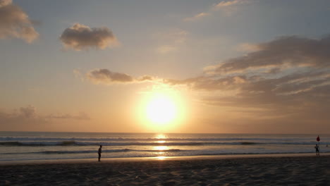 Silhouette-Junge-Am-Schönen-Strand-Von-Bali-Bei-Sonnenuntergang,-Der-Ball-Mit-Wellen,-Ozean,-Himmel,-Wolken,-Sand-Und-Meer-Tritt