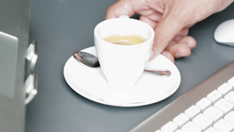Die-Rechte-Männliche-Hand-Wischt-Eine-Espressotasse-über-Den-Tisch-Zwischen-Tastatur,-Maus-Und-Laptop