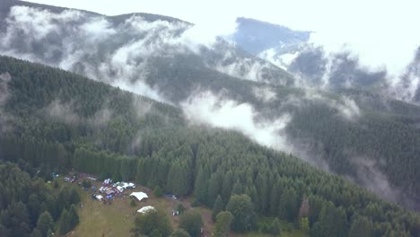 Luftdrohnenaufnahme-Eines-Festival-Campingplatzes,-Der-Die-Weite-Des-Rumänischen-Berghangs-Enthüllt,-Der-Vom-Talnebel-Des-Frühen-Morgens-Bedeckt-Ist