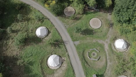 Aerial-top-down-shot-tracking-forward-over-a-group-of-tents-or-often-referred-to-as-Yurts-or-roundhouses