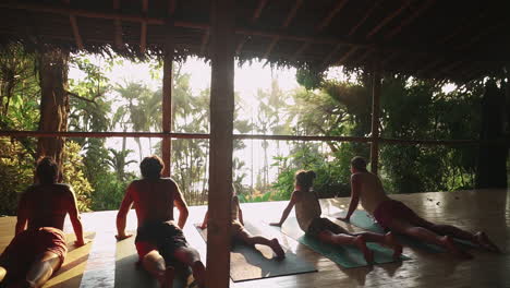 Eine-Familie-Von-Reisenden-Genießt-Eine-Meditations--Und-Yoga-Sitzung-Bei-Sonnenuntergang-Auf-Einer-Holzveranda-Mit-Blick-Auf-Den-Regenwald-Und-Den-Dschungel,-Der-Zum-Strand-Führt