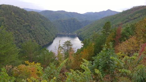 A-dam-and-lake-surrounded-by-the-Great-Smoky-Mountains-National-Park-with-scenic-autumn-trees-Calderwood-Dam-filmed-from-The-Tail-of-the-Dragon-Scenic-Overlook