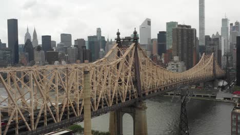 Full-drone-aerial-pan-of-the-Queensboro-Bridge-from-Manhattan,-NYC-to-Queens-in-the-daytime-with-a-bus-leaving-Manhattan,-Poetic-view-of-someone-leaving-the-big-city